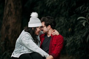 Casal com o rosto colado em meio a natureza