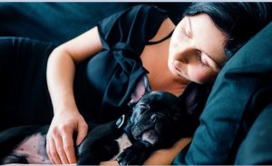 Mulher dormindo com cachorro no colo