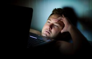 Homem deitado mexendo no computador