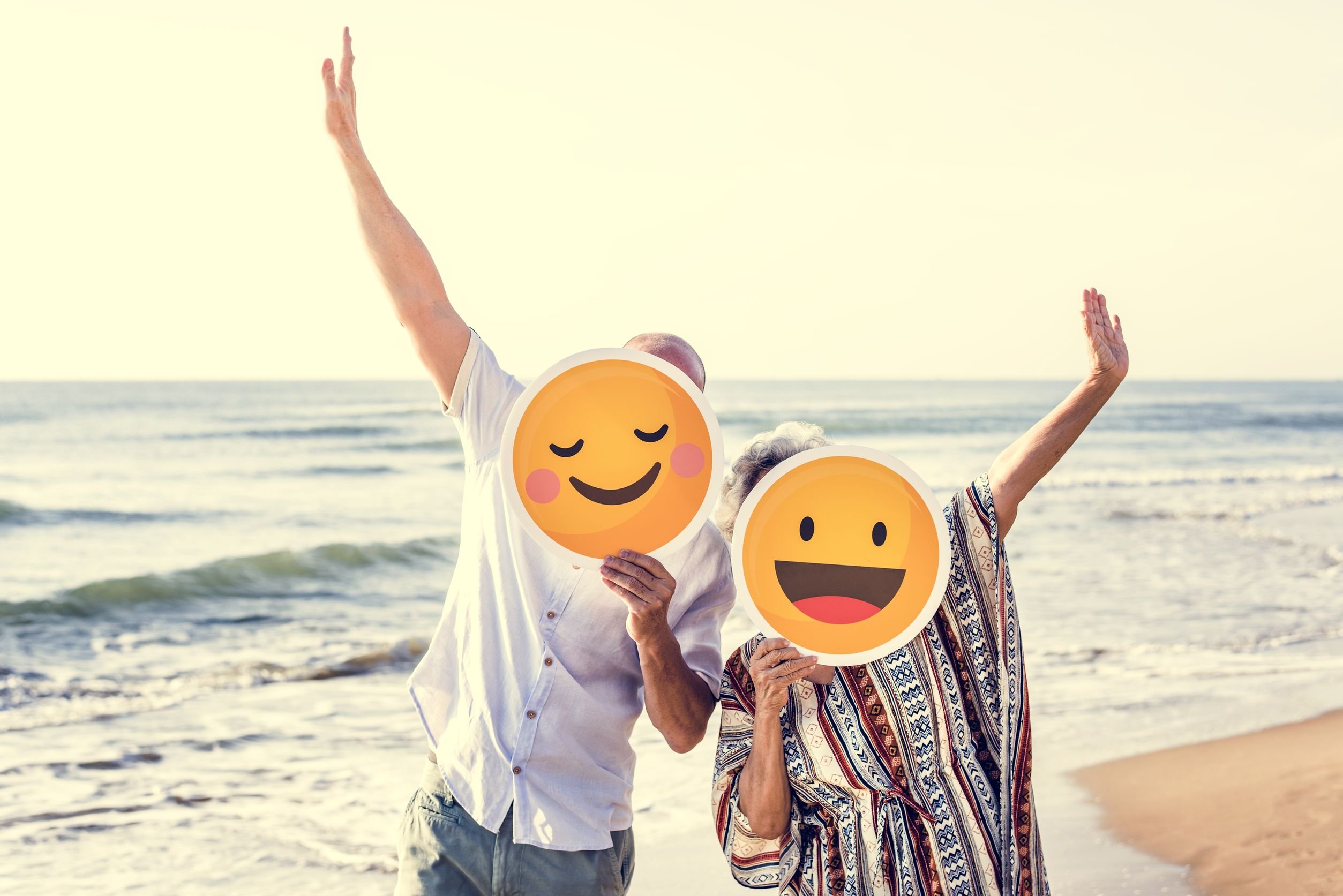 Pessoas com marcara de emoji na praia