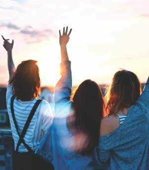 Mulheres de frente ao sol com as mãos pra cima