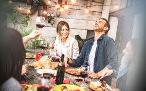 Homem sorrindo olhando para o alto rodeado de amigos em um happy hour