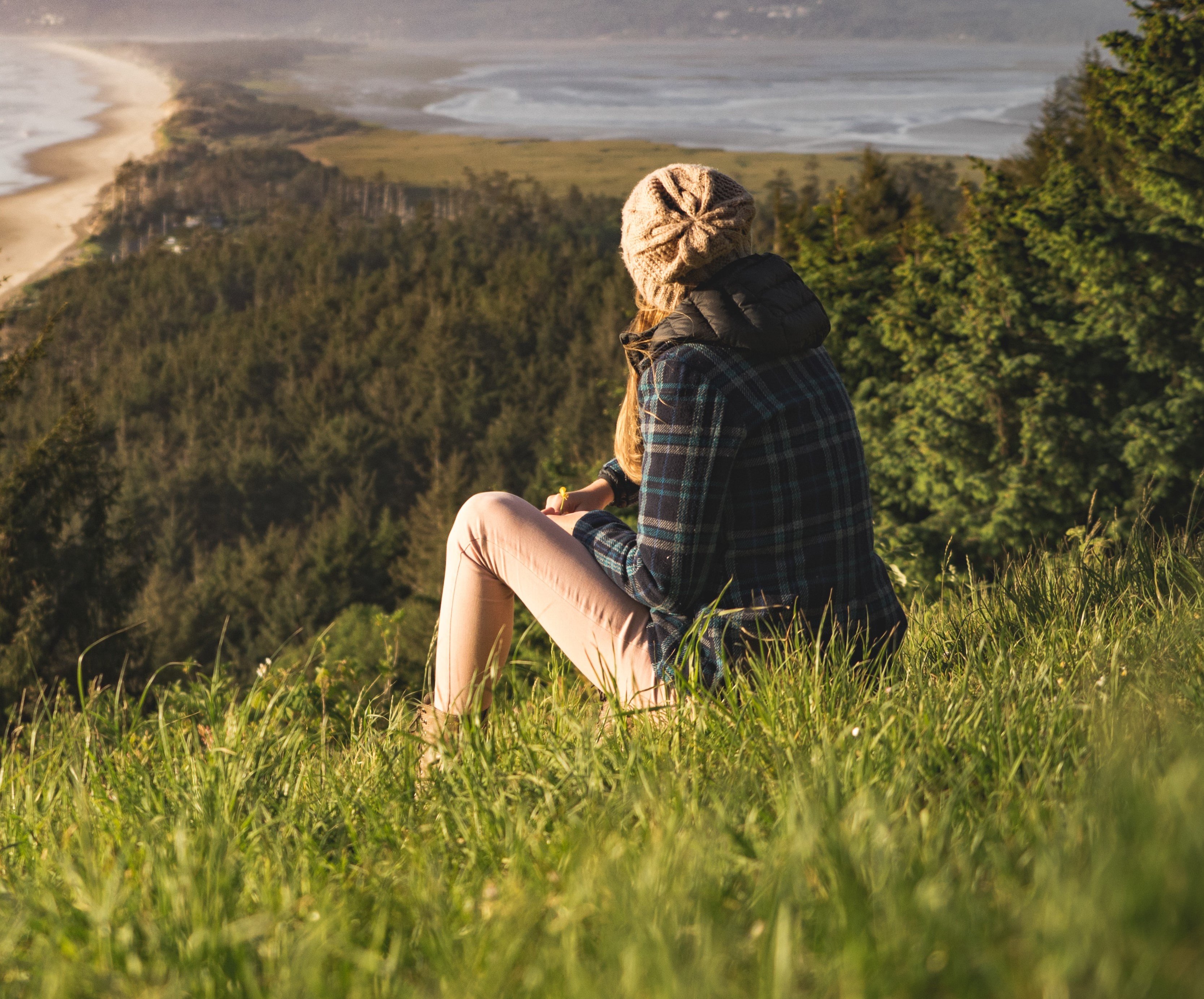 Mulher sentada no gramado olhando para o horizonte