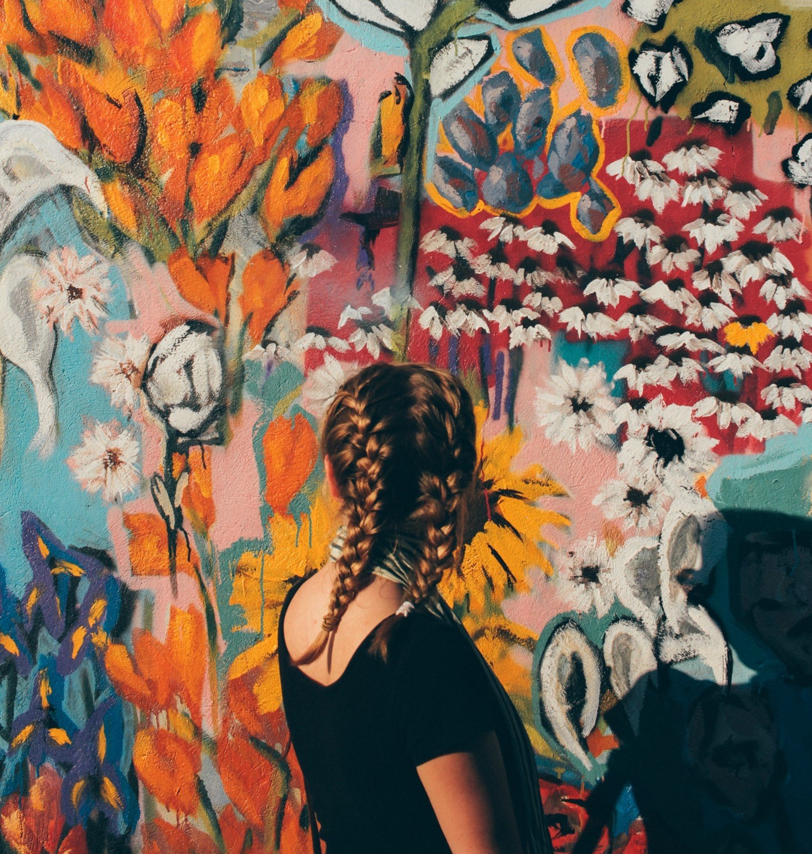 Mulher de frente para uma parede pintada de flores