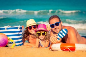 Pais e filha deitados na areia da praia