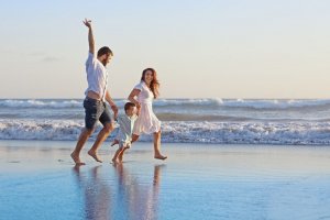 Casal com criança andando na beira do mar
