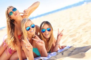 Amigas deitadas na areia da praia sorrindo