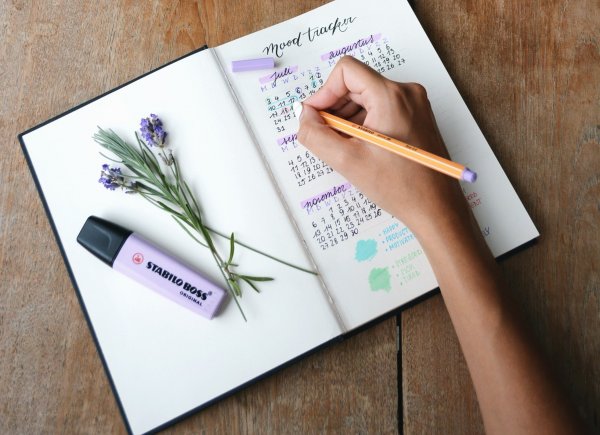 Pessoa escrevendo na agenda com calendário