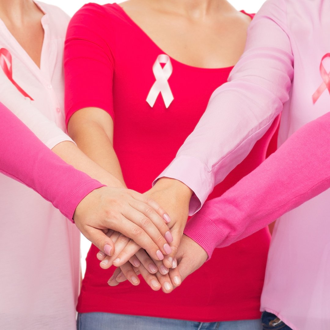 Várias mulheres com as mãos juntas, em referência à luta ao câncer de mama