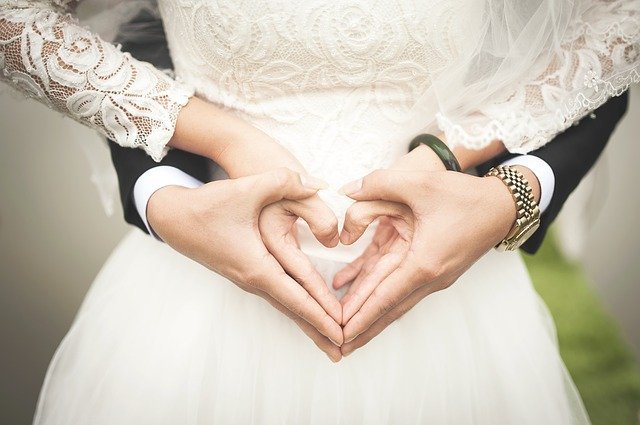 Noivo e noiva de mãos juntas formando coração