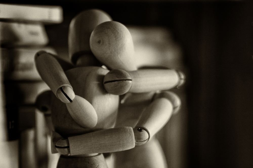 Dois bonecos de madeira se abraçando.