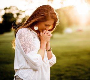 Por: Ben White - Unsplash Mulher rezando em um campo