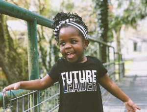 por: Kiana Bosman Criança sorrindo no parque segurando grade