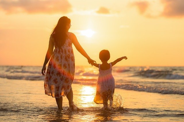 Mãe e filha andando na praia