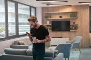 Pexels Homem em sala de estar segurando o telefone e rindo.