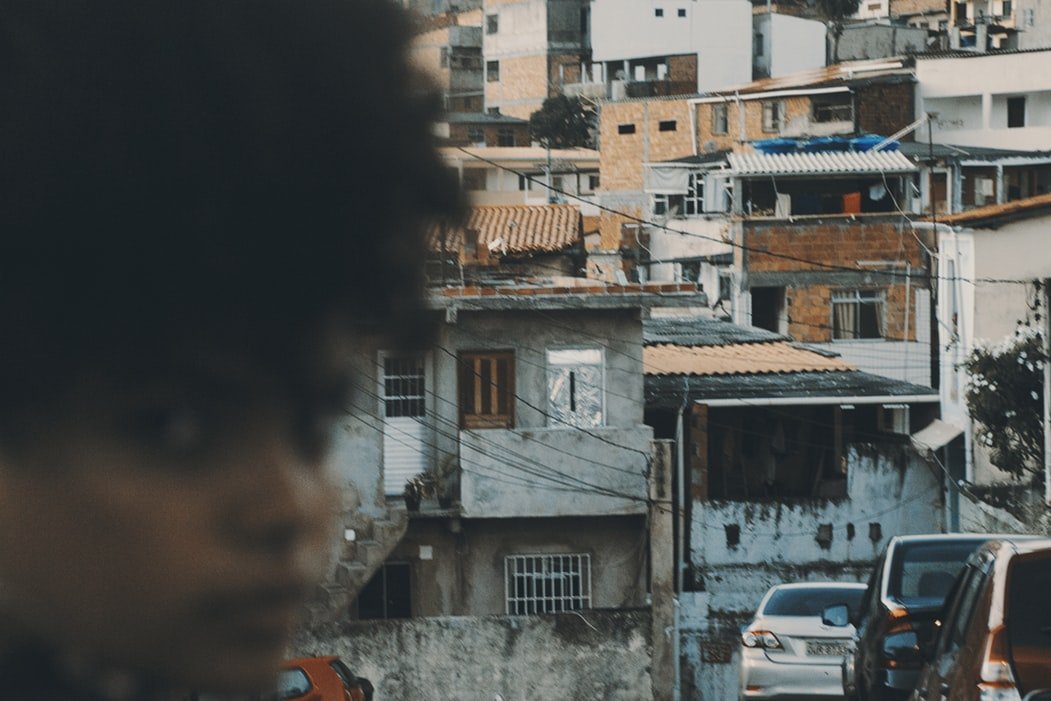 Mulher desfocada em frente a uma favela brasileira