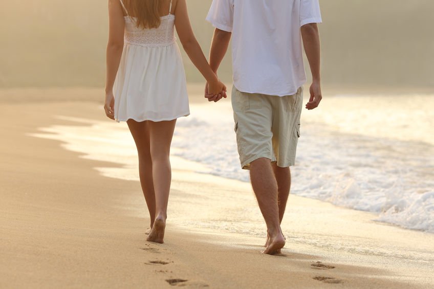 Casal de mãos dadas andando na praia