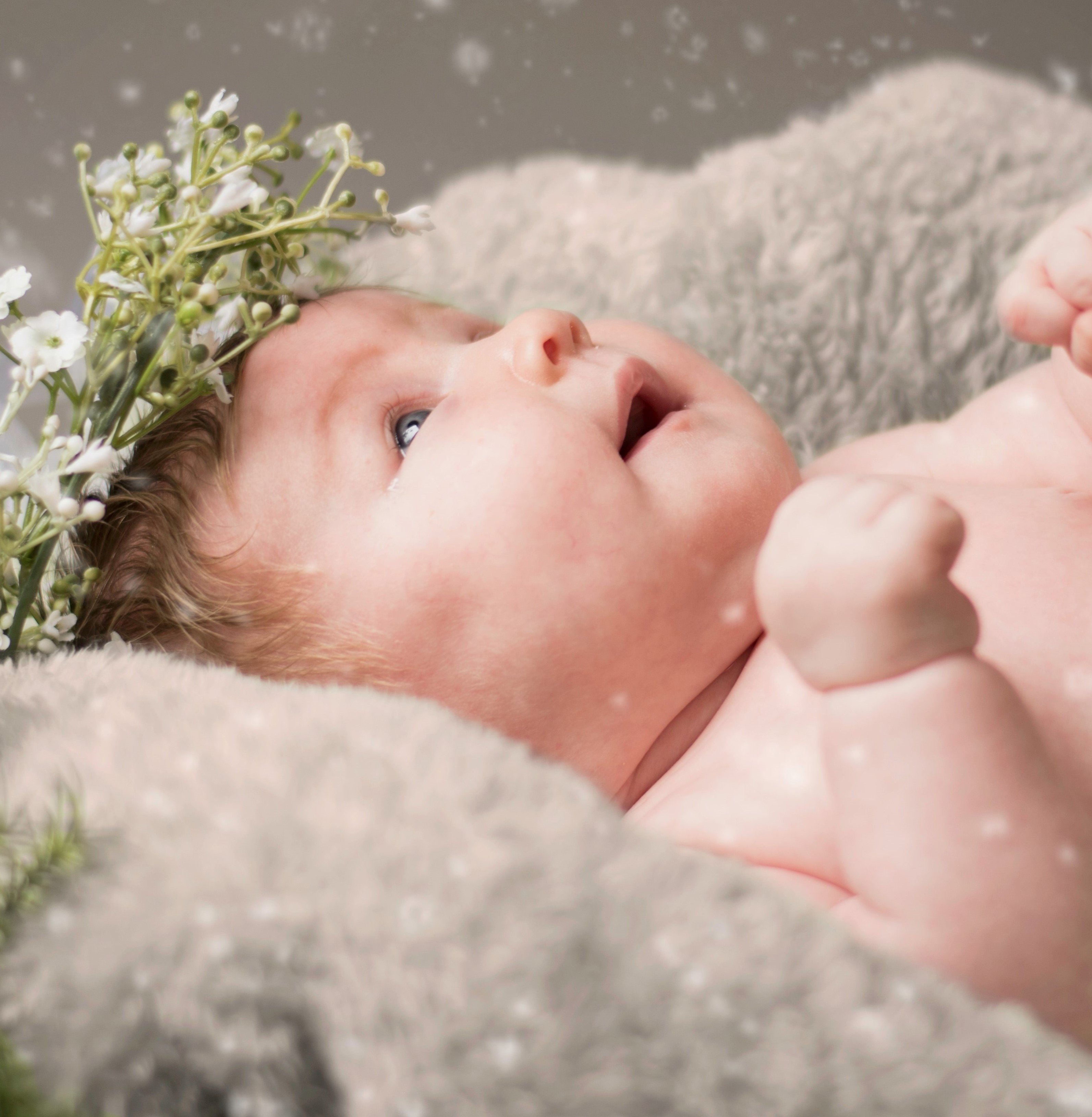 Bebê com uma coroa de flores e neve caindo