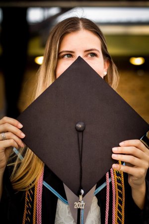 Por: Kailey Krupar - Reshot Mulher segurando chapéu da formatura no rosto