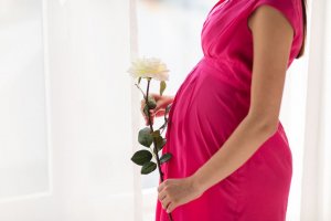 123rf. Mulher grávida segurando uma flor.