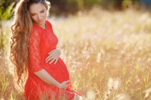 123rf. Gestante sorrindo com as mãos na sua barriga.