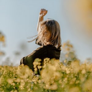 Unsplash - por Esther Driehaus Mulher de pé em um campo de flores.