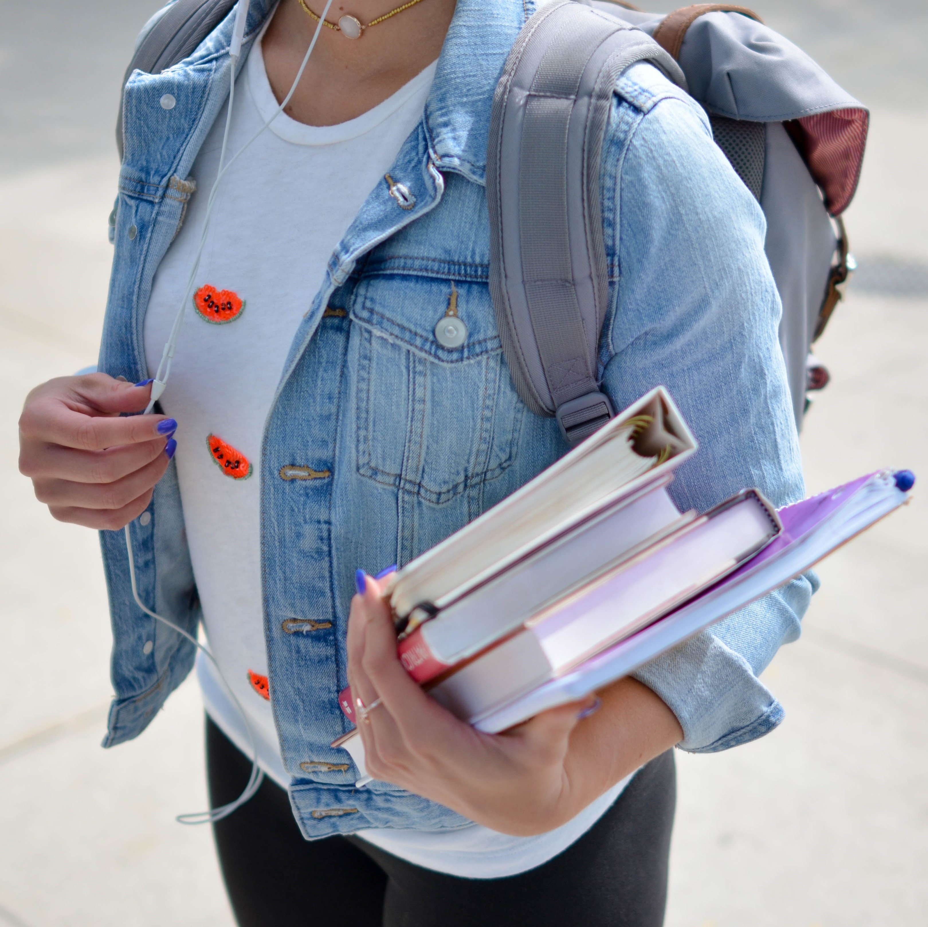 Mulher segurando cadernos da faculdade e mochila