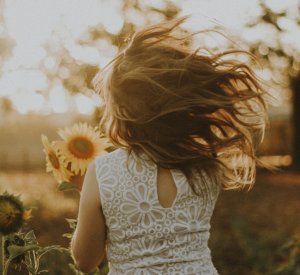 Rodolfo Sanches Unsplash Mulher segurando girassóis andando no gramado
