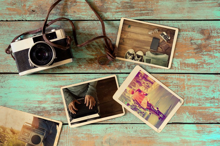 Álbum de fotos e uma câmera retro em cima de uma mesa de madeira.