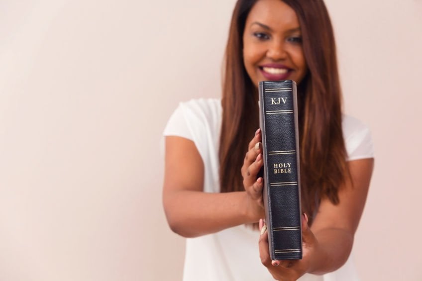 Menina sorrindo e mostrando sua Bíblia de King James