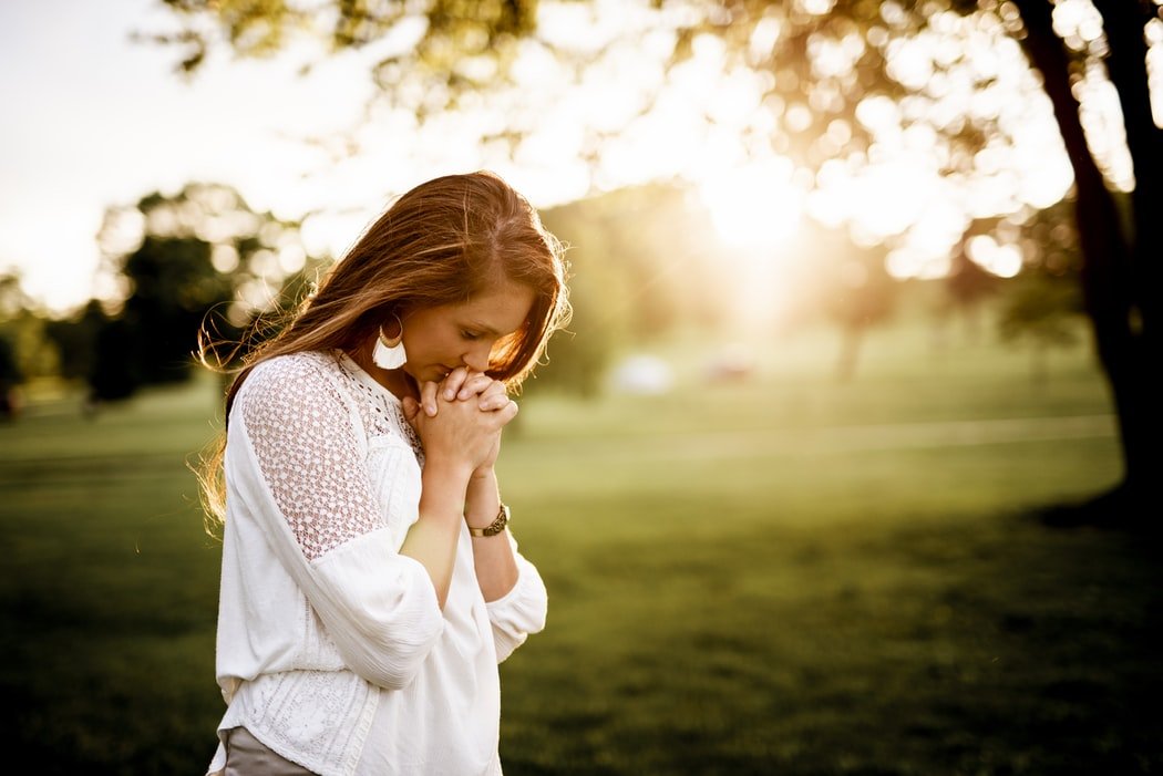 Unsplash - por Ben White Mulher rezando em parque