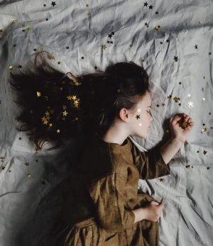 Unsplash/Annie Spratt Menina deitada com estrelas na cama, rosto e cabelos