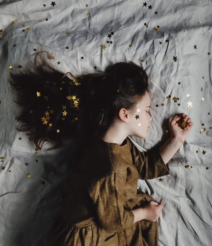 Menina deitada com estrelas na cama, rosto e cabelos