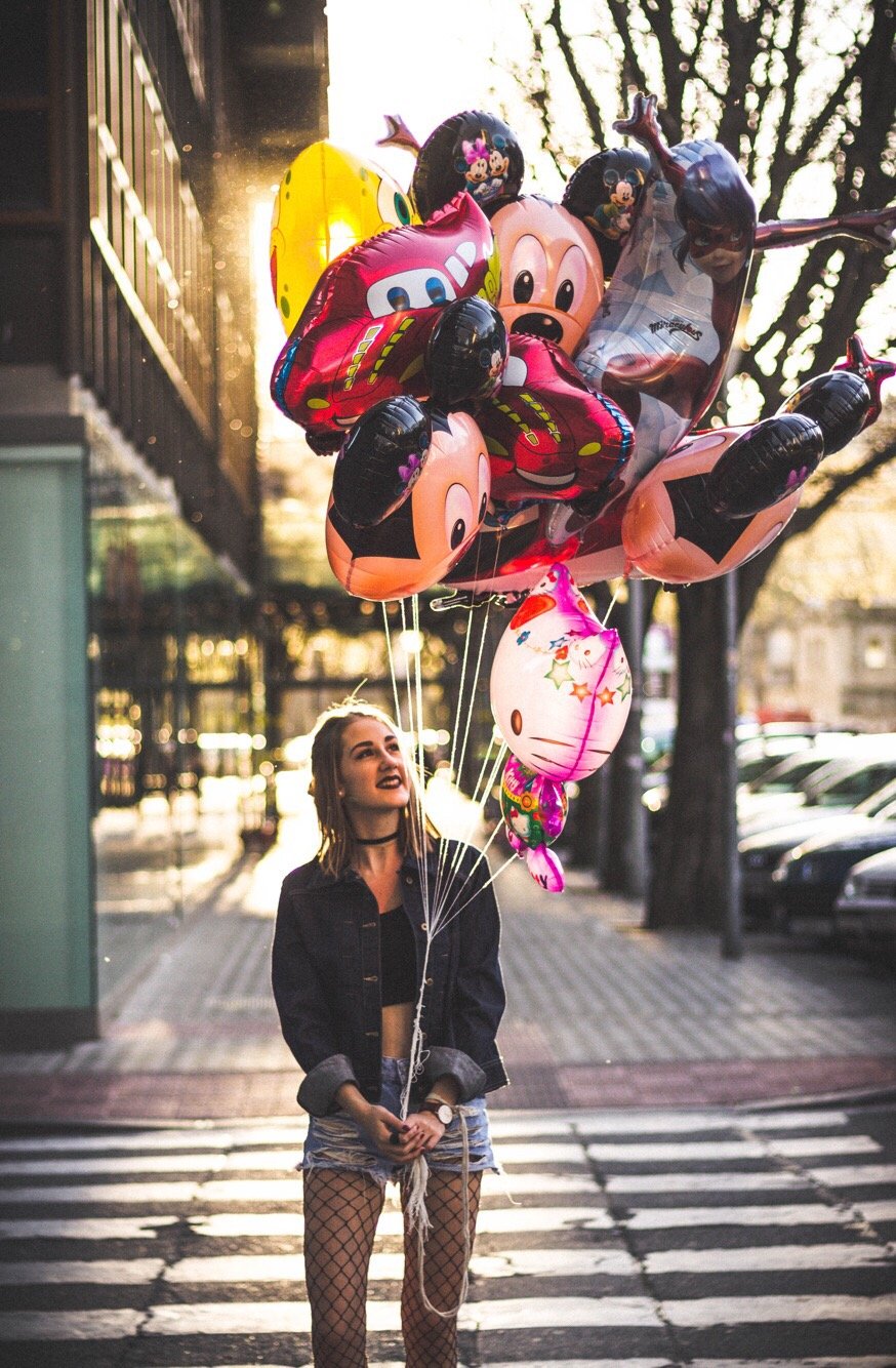 Mulher na calçada segurando balões