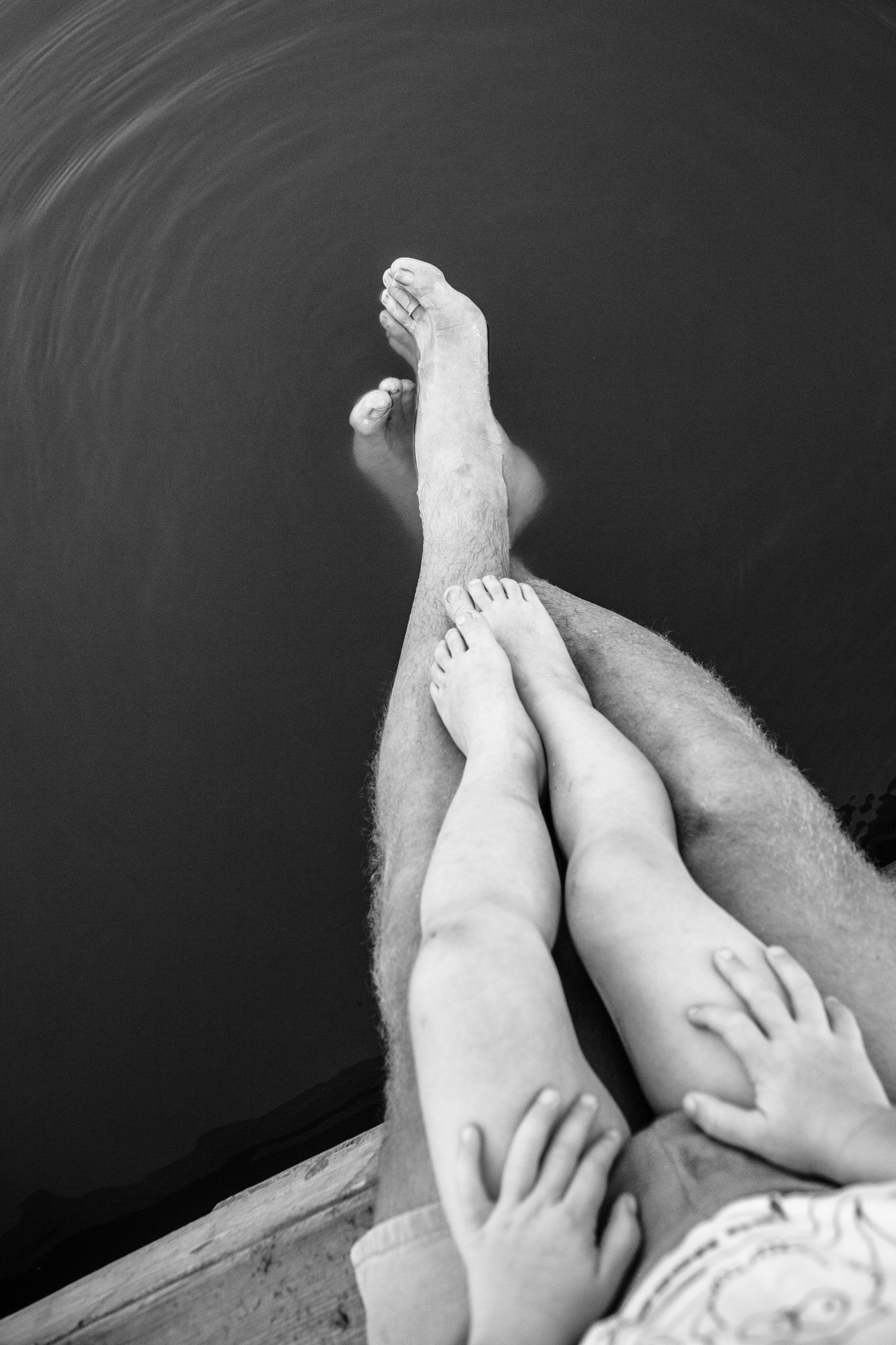 Pai e filha com pernas na água