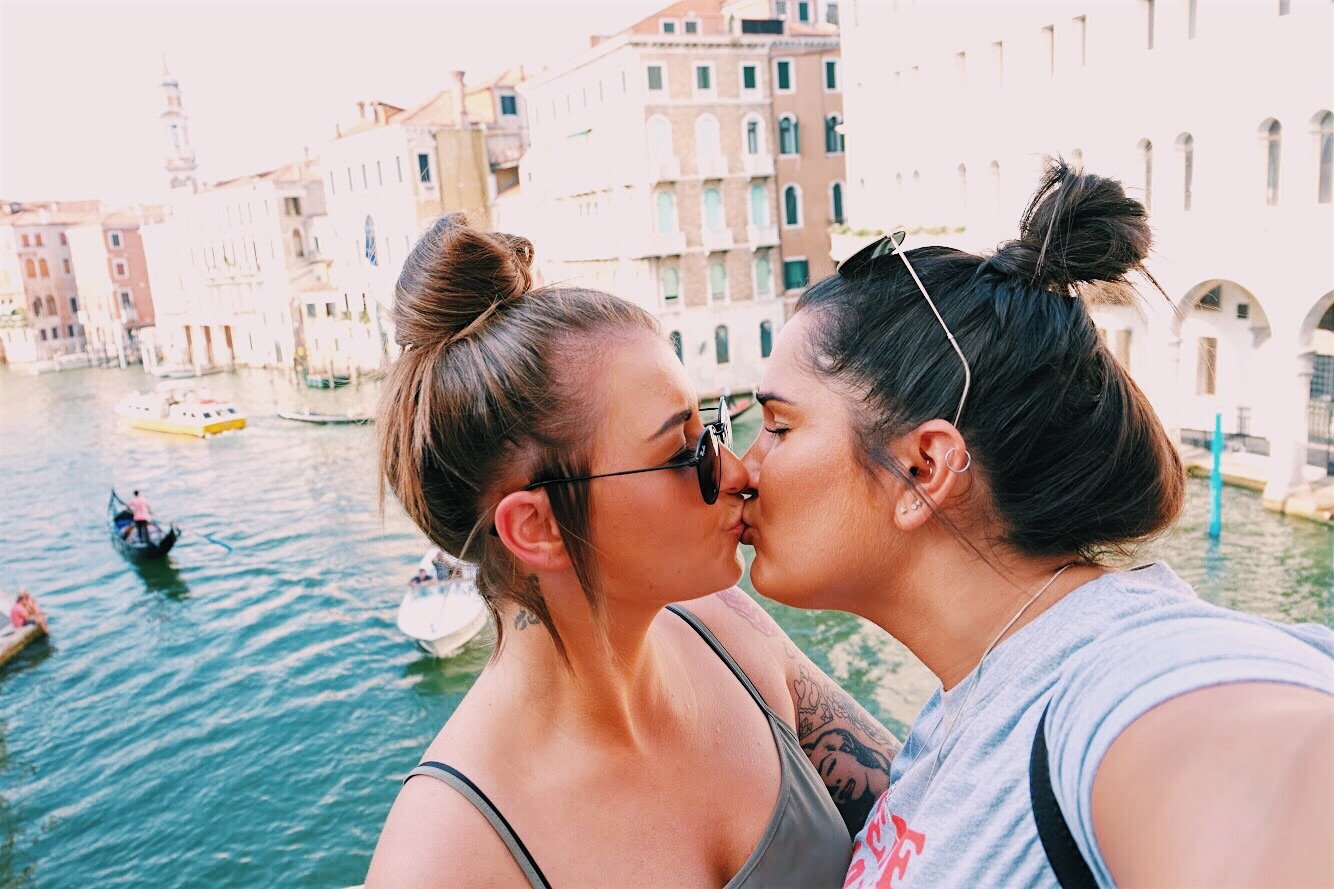 Duas mulheres se beijando e no fundo um lago