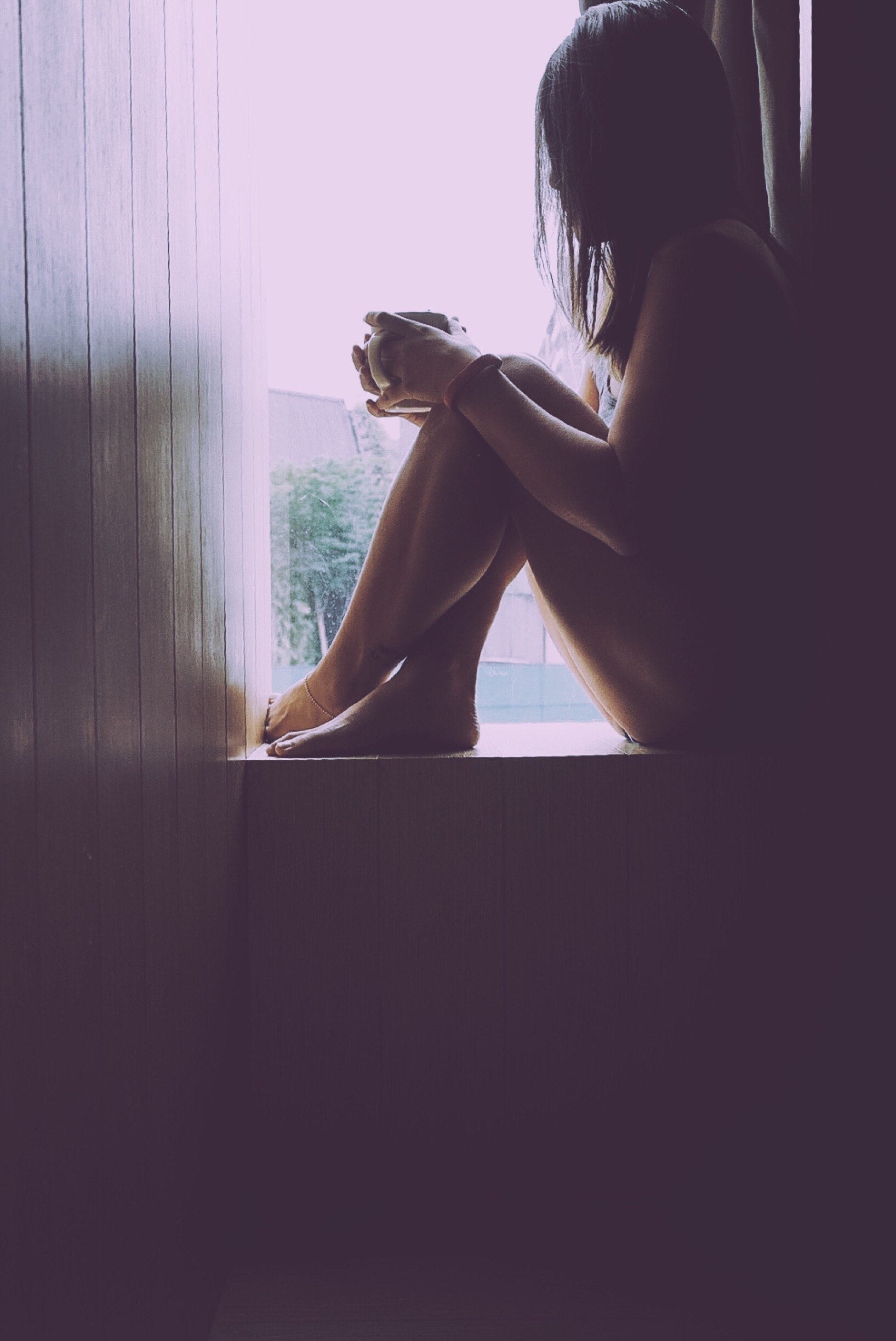 Mulher sentada na janela segurando uma xícara