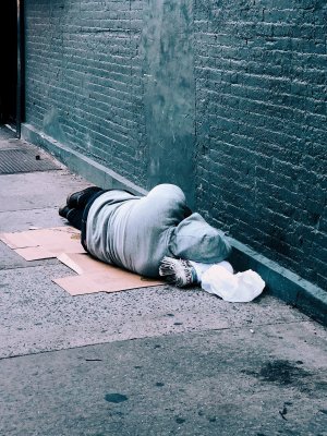 Jon Tyson - Unsplash Morador de rua deitado na calçada