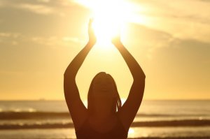 123rf Mulher de braços erguidos e mãos iluminadas pelo Sol