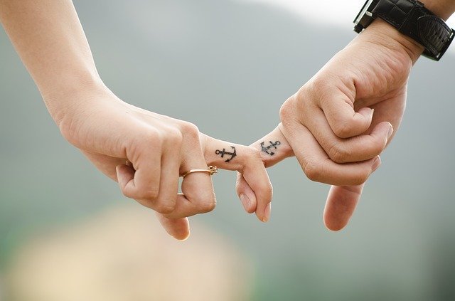 Mãos juntas e dedos com tatuagens iguais de âncora
