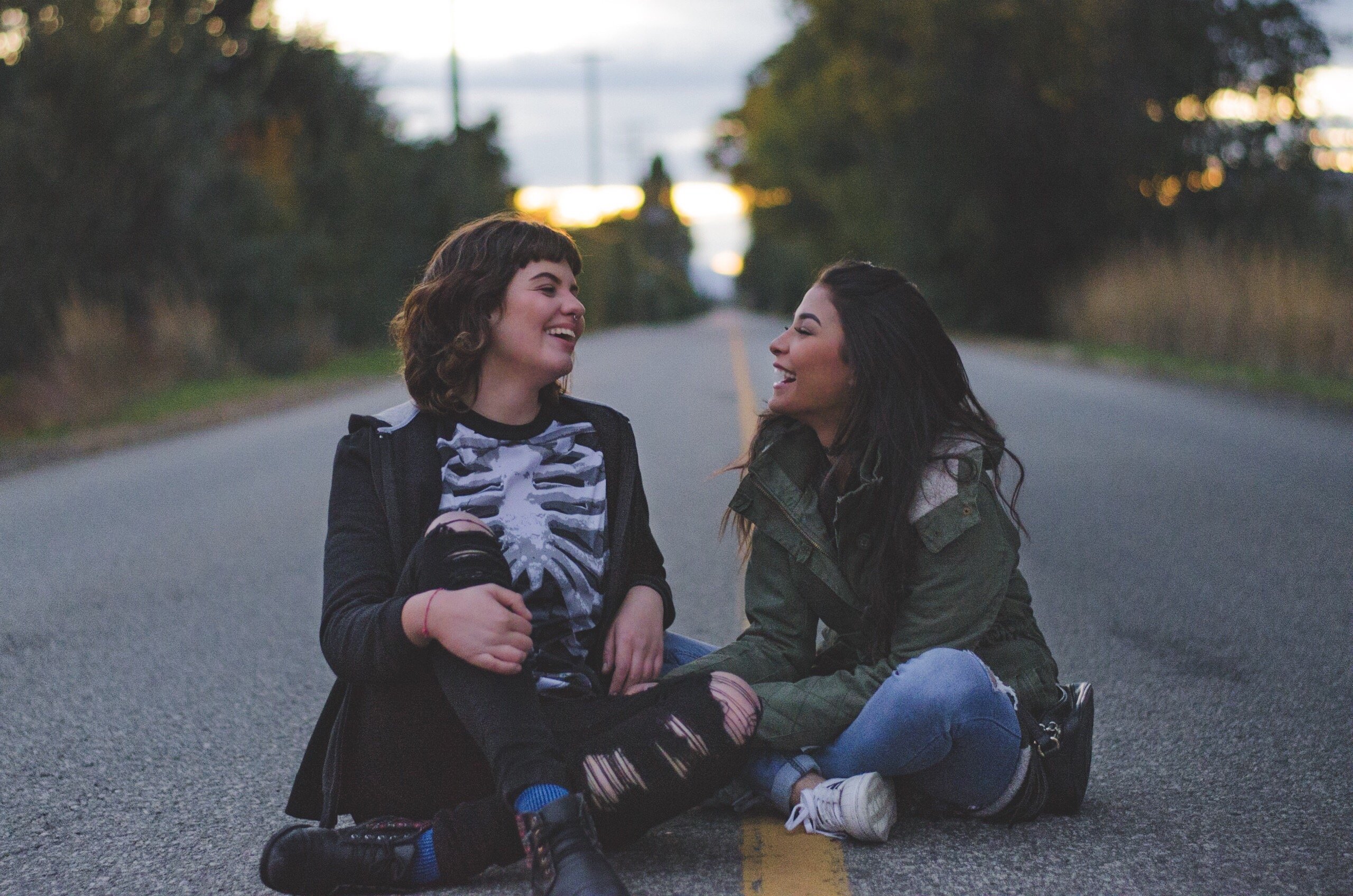 Duas mulheres sentadas no meio da rua rindo