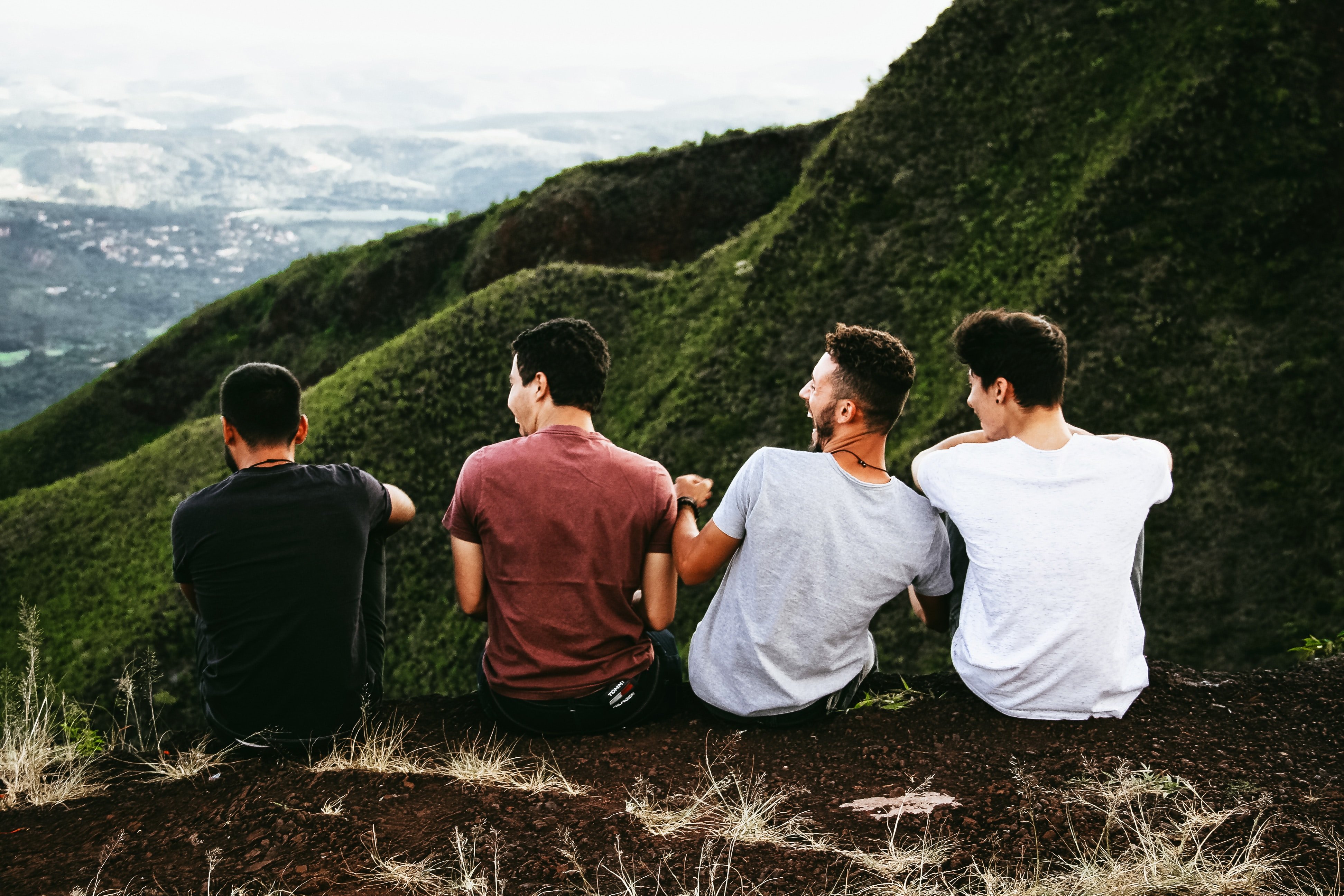 Amigos sentados em pedra com montanhas ao fundo