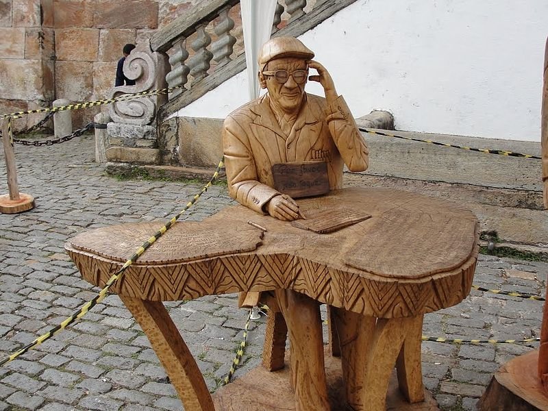 Escultura em madeira de Chico Xavier psicografando.