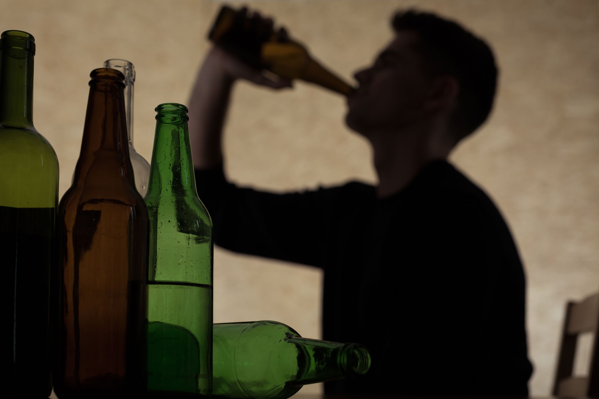 Sombra de um homem tomando bebida na garrafa