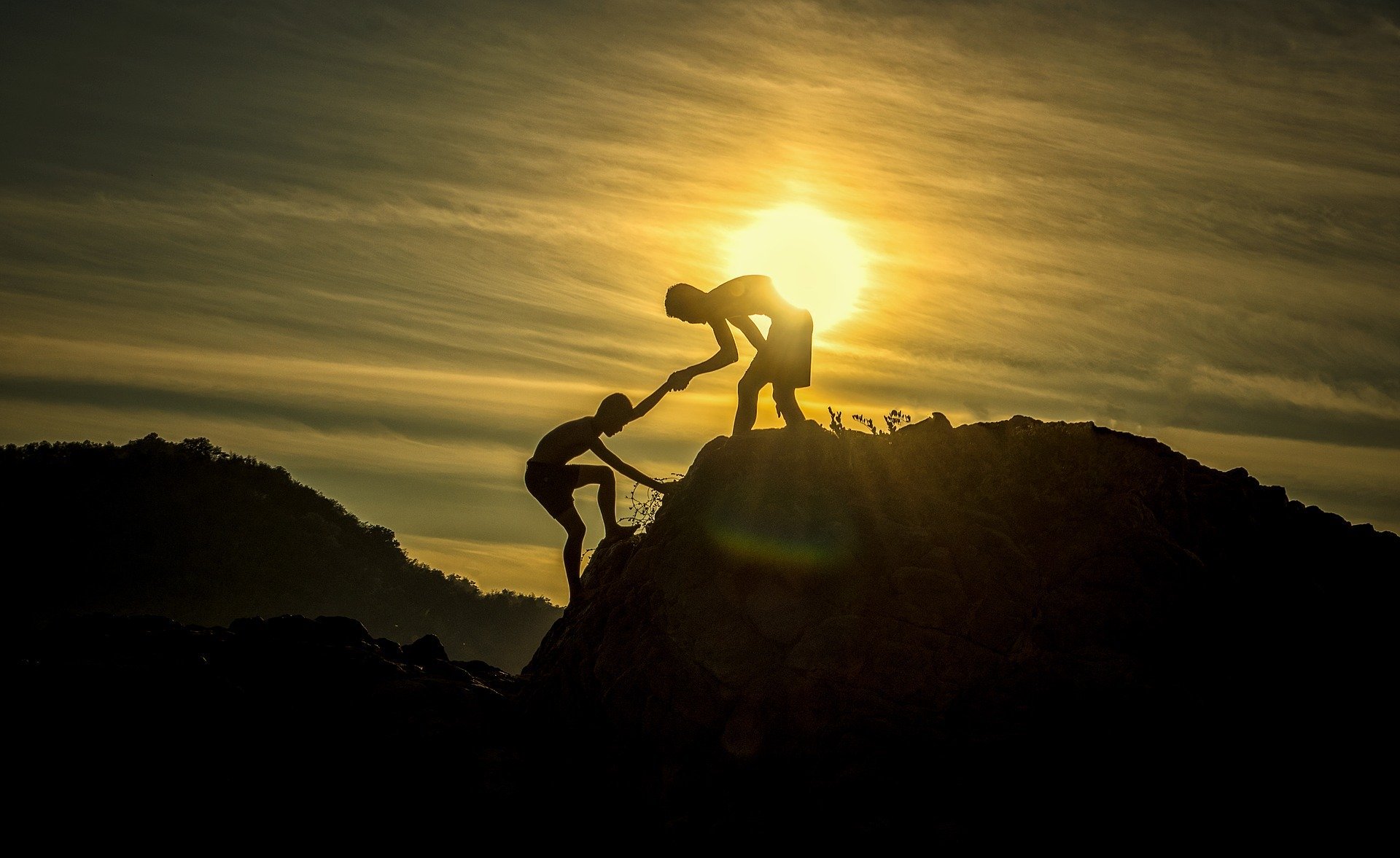Homem ajudando outro homem a subir a montanha