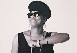 GH Queen Latifah sorrindo apoiando em uma cadeira