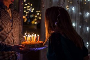 Sergei Solo/Unsplash Mulher apagando velas do bolo.