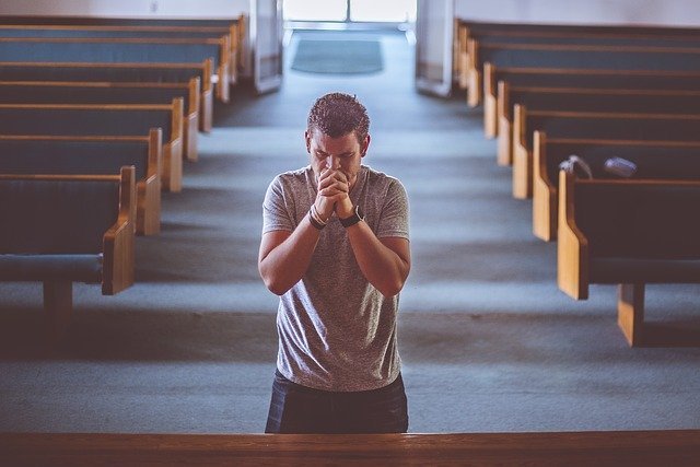 Homem ajoelhado em igreja orando