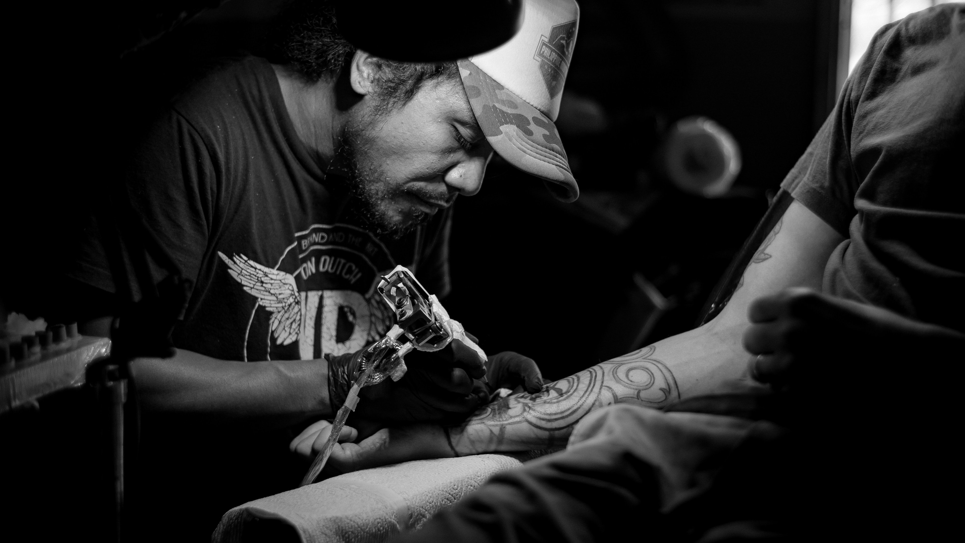 Tatuador trabalhando no braço de um homem.