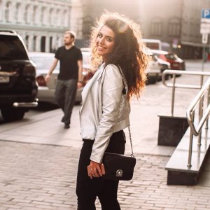 Anna Golubeva Reshot Mulher na calçada de lado sorrindo